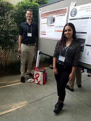 Aysha and Calvin standing next to their poster at SCAS meeting